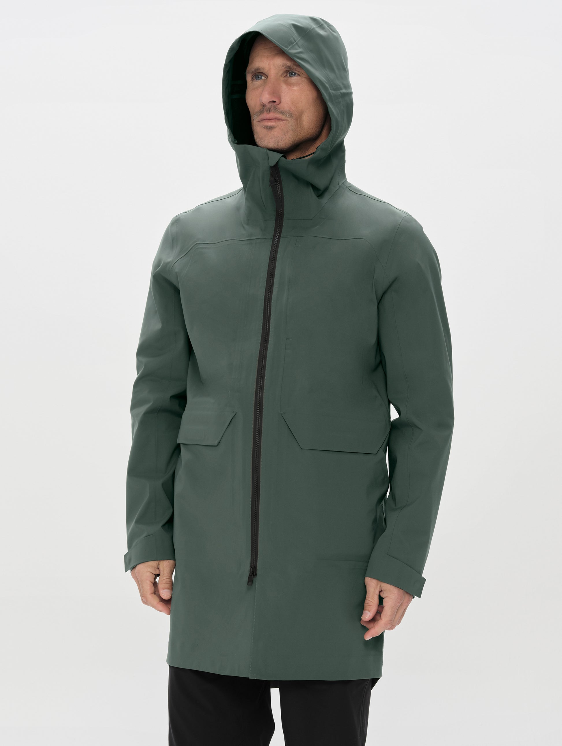 Front upper-body view of man wearing the Wallace Rain Parka in Saville Green from AETHER Apparel zipped up. 