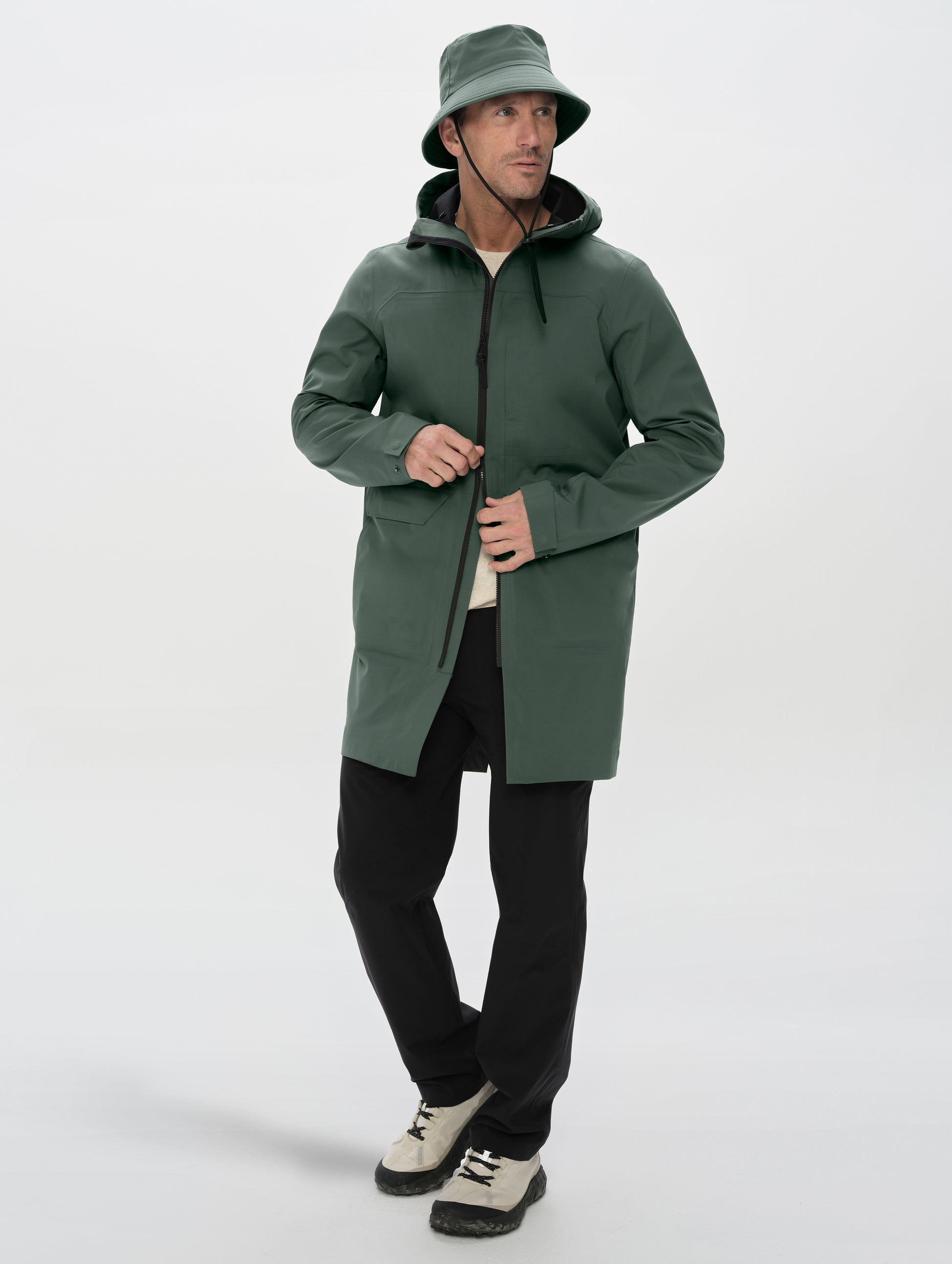 Full-body view of man wearing the Wallace Rain Parka in Saville Green from AETHER Apparel unzipped. 