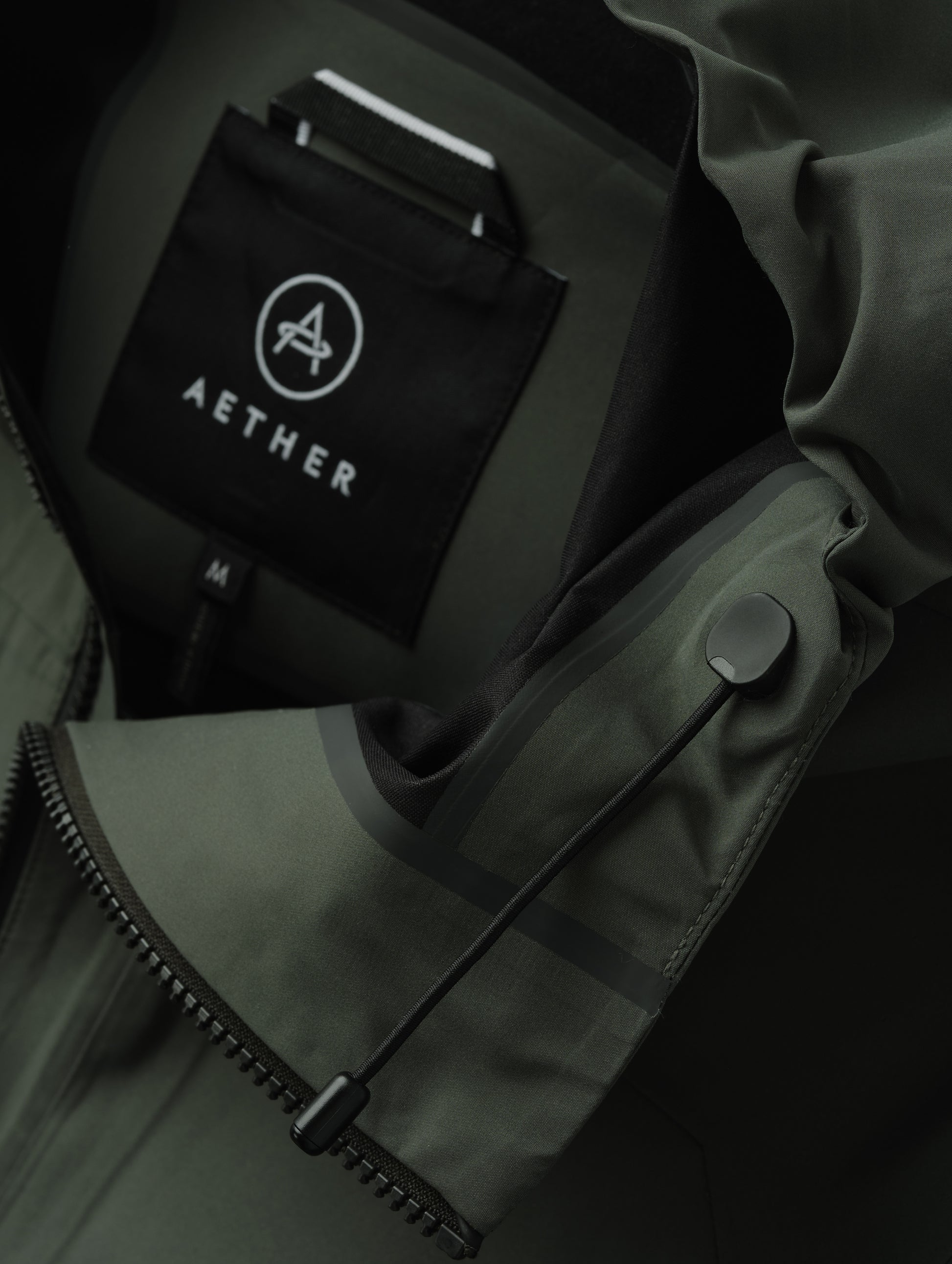 Closeup detailed view of the bungee system on the hood of the men's Wallace Rain Parka in Saville Green from AETHER Apparel.