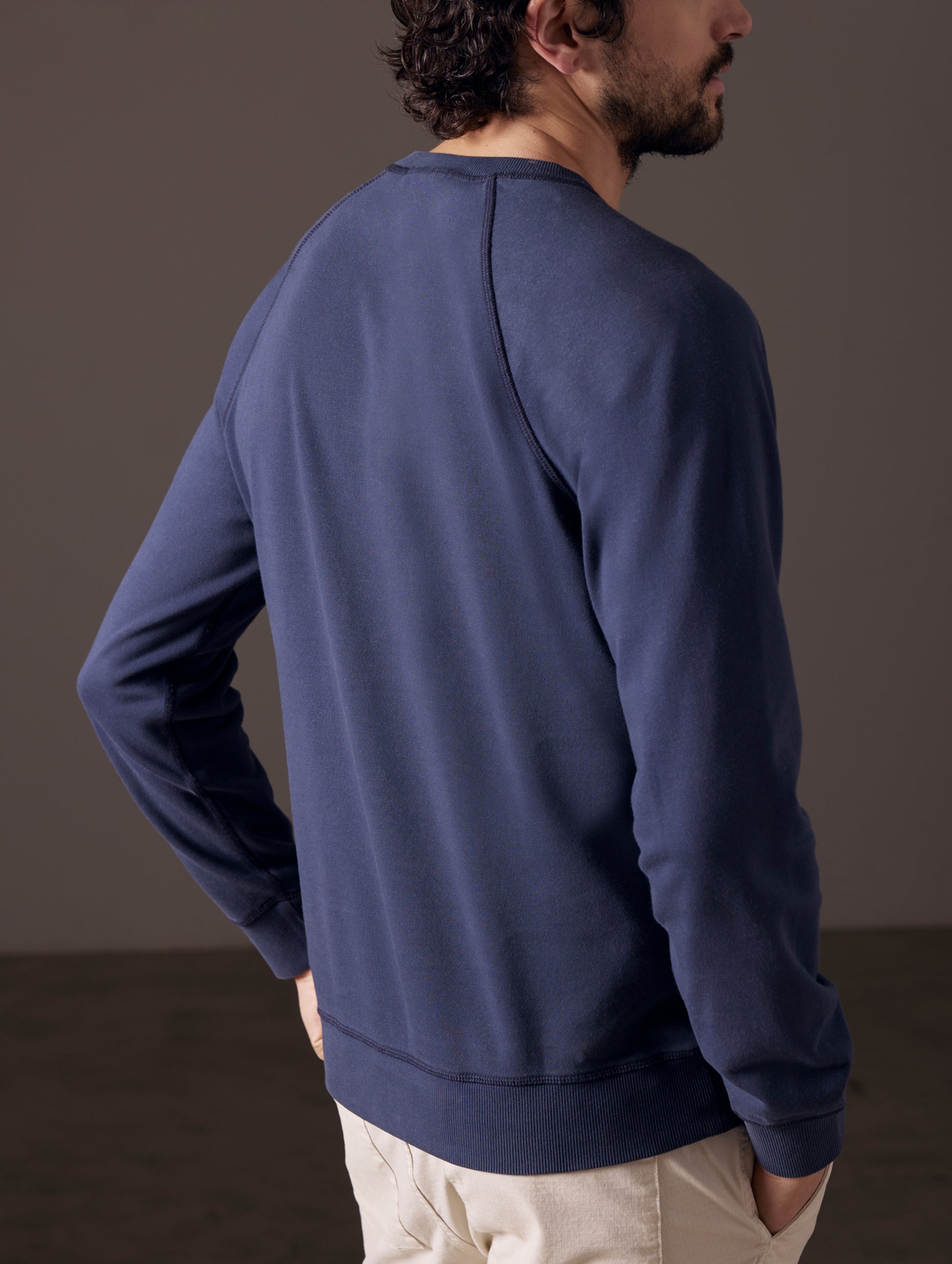 Back view of man wearing blue crew sweatshirt