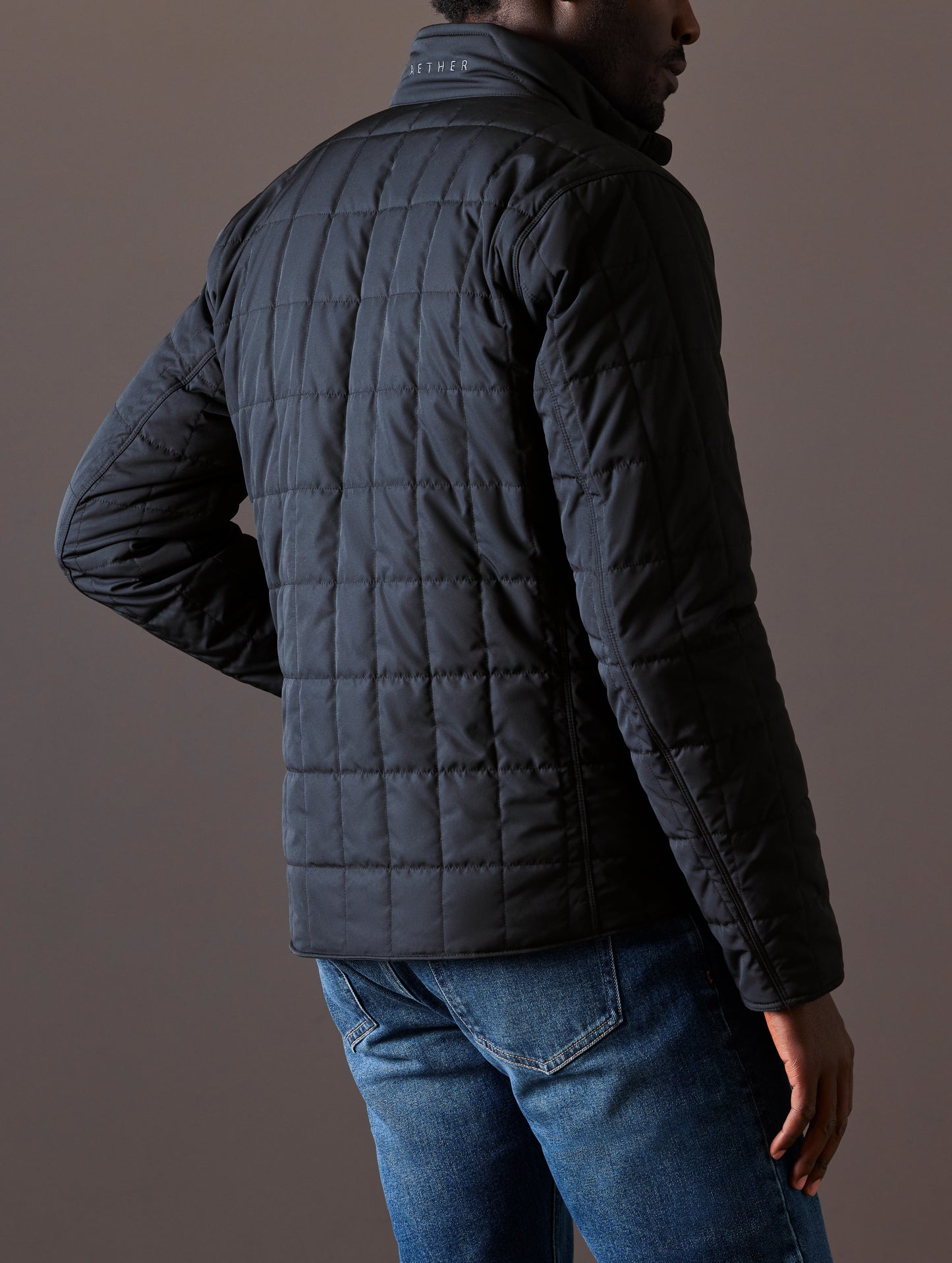 Back view of man wearing black quilted jacket