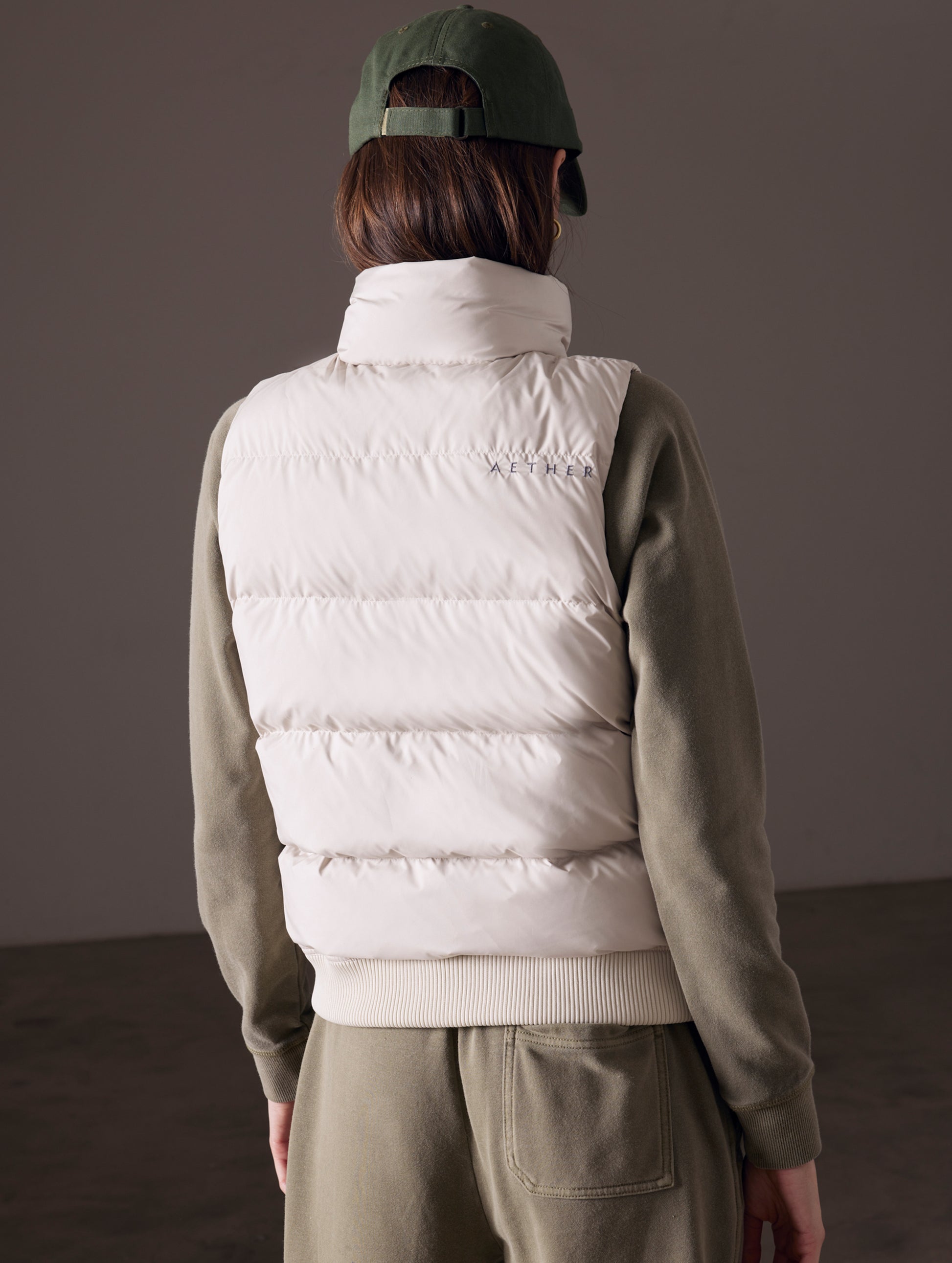 back view of woman wearing beige insulated vest from AETHER Apparel