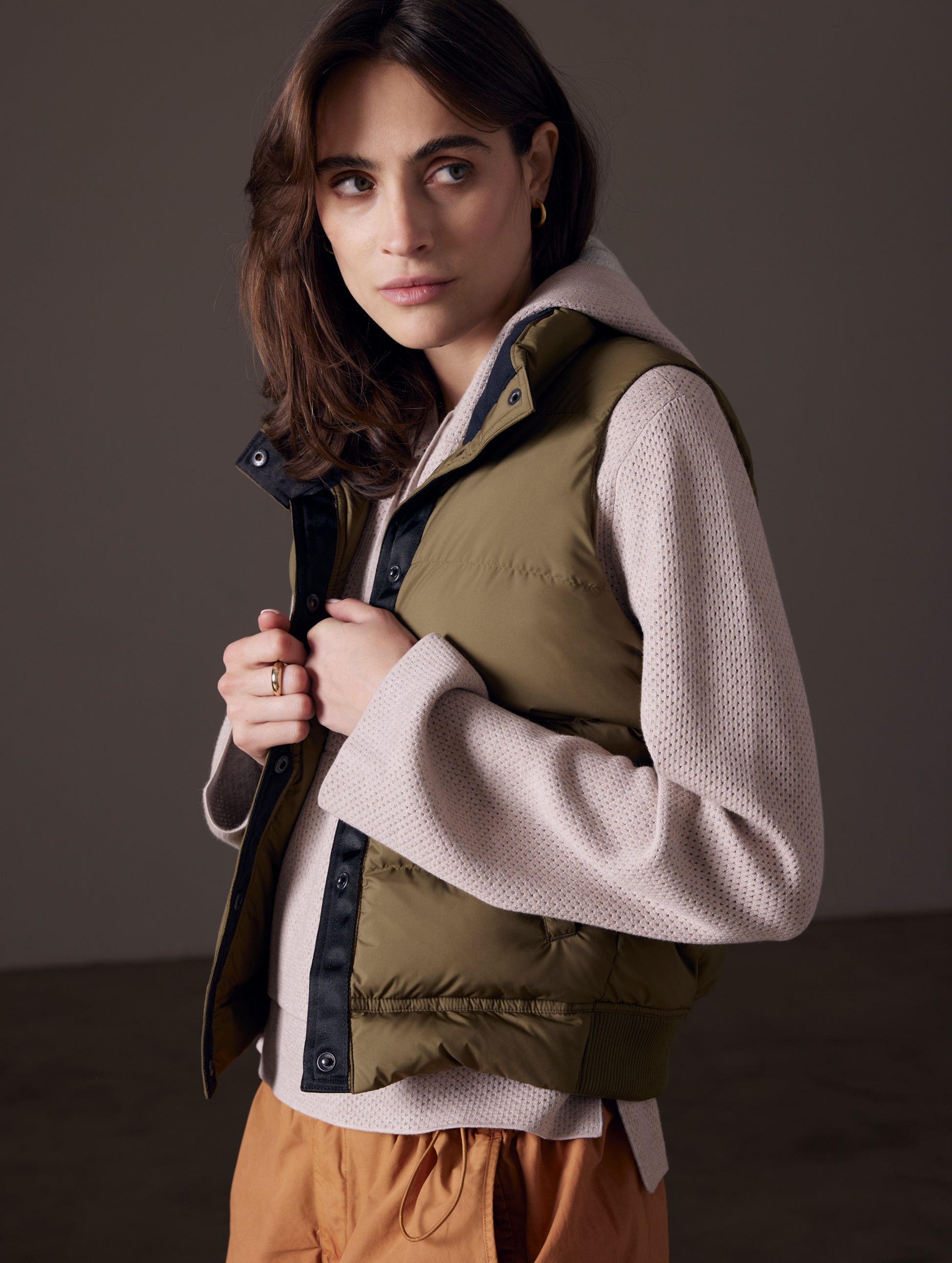 Front 3/4 view of woman wearing green insulated vest from AETHER Apparel.