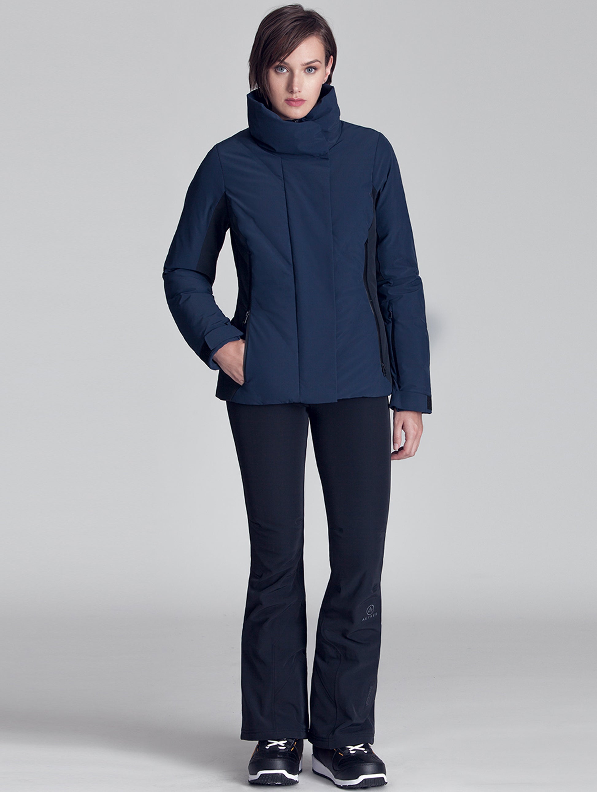 Full-body view of woman wearing blue Vertical Jacket from AETHER Apparel.