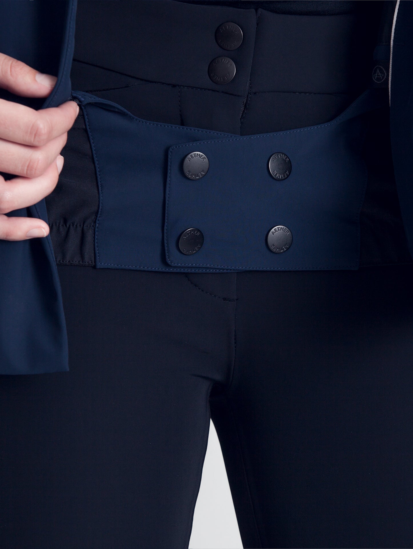 Close view of woman wearing blue Vertical Jacket AETHER Apparel with snapped waist adjuster.